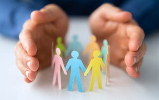 A man's hands holding a group of colored paper people, providing Proposal Support for the Federal Government. | Revolutionary Solutions A man's hands holding a group of colored paper people, providing Proposal Support for the Federal Government.